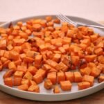 Baking sweet potato cubes in an airfryer on a plate